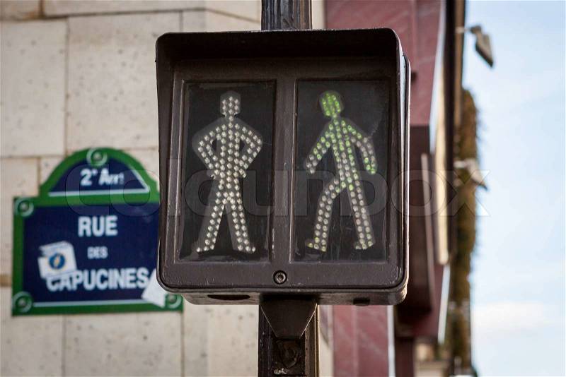 Pedestrian traffic lights at an intersection showing a figure standing and walking which will illuminate green to allow pedestrians to cross the street or red to warn them to wait before crossing, stock photo