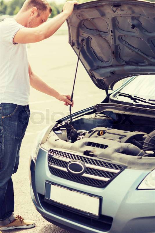 Transportation and vehicle concept - man opening car bonnet and looking under hood, stock photo