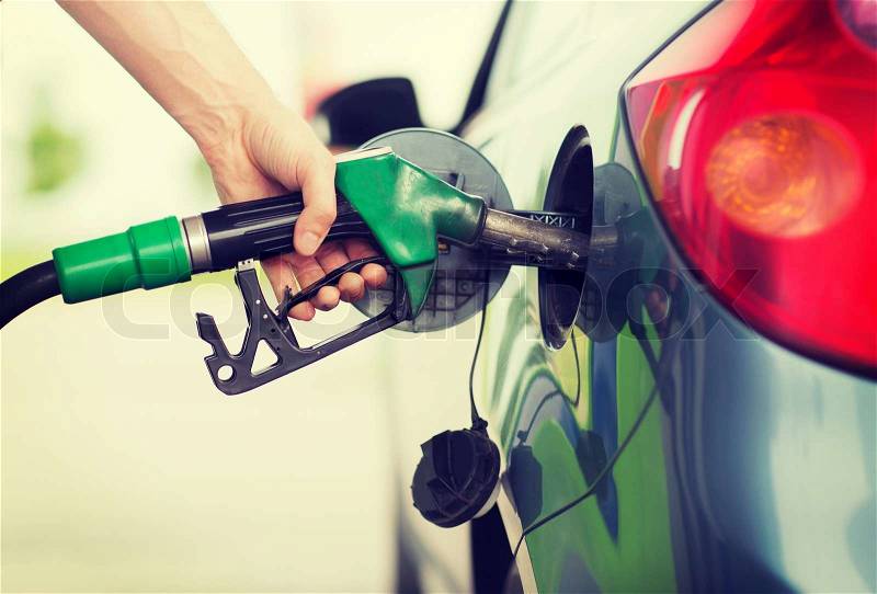 Transportation and ownership concept - man pumping gasoline fuel in car at gas station, stock photo