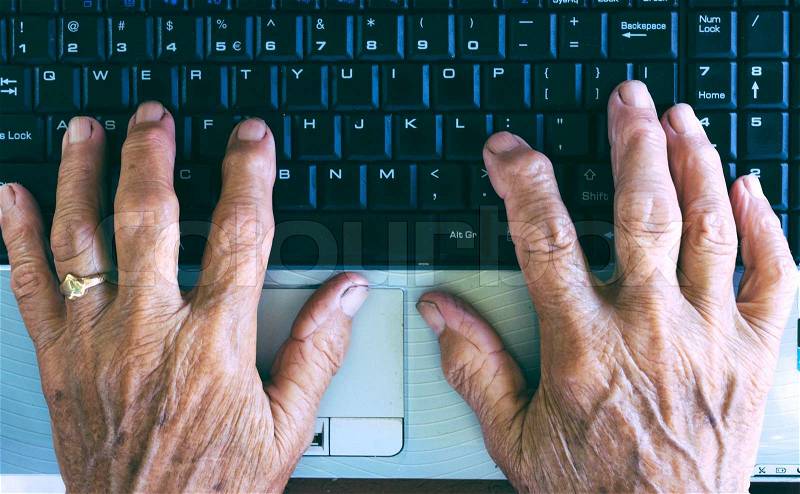 Old hands typing on the computer keyboard from above , stock photo
