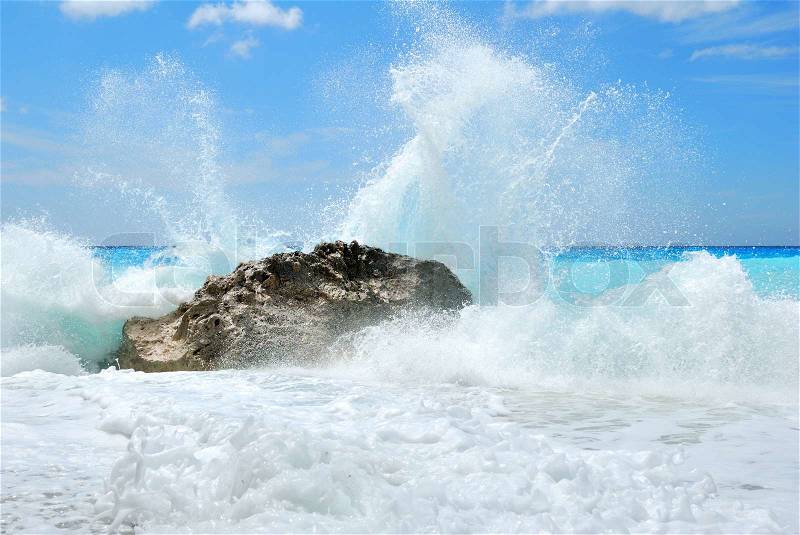 Big sea wave breaking on the shore rocks with a high sea spray, stock photo