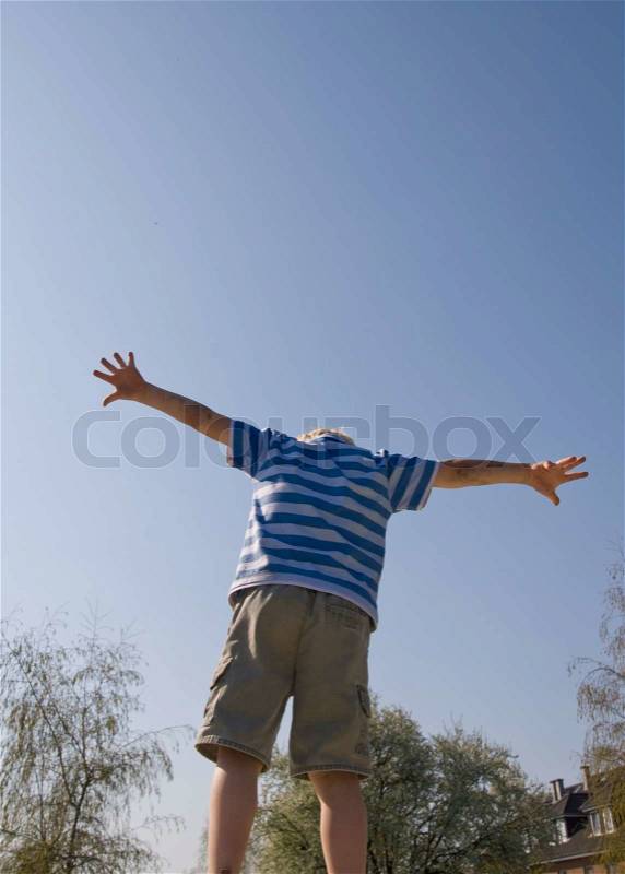 A young boy with arms outstretched on a spring day, stock photo