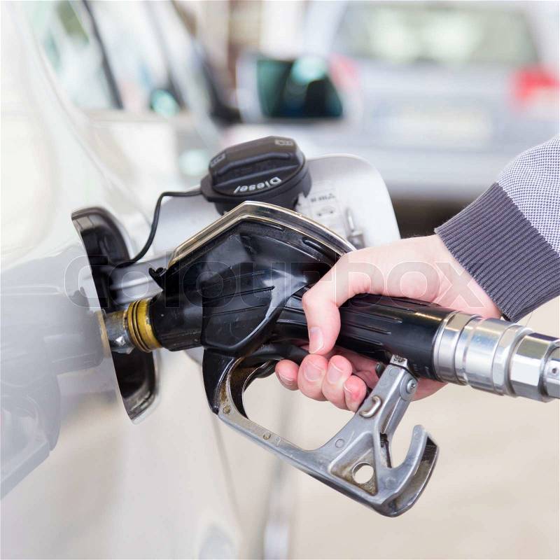 Petrol or gasoline being pumped into a motor vehicle car. Closeup of man pumping gasoline fuel in car at gas station, stock photo