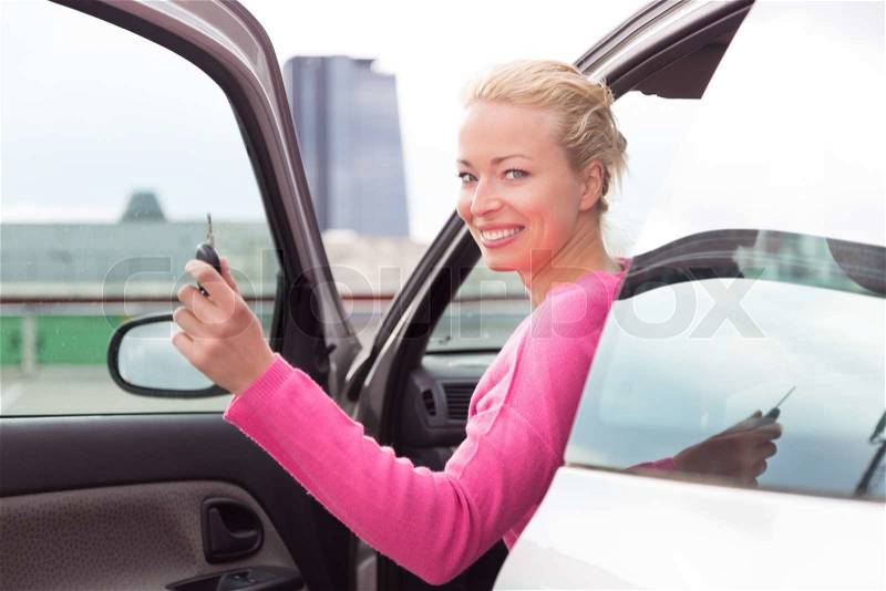 Woman driver showing car keys. Young female driving happy about her new car or drivers license. Caucasian model, stock photo