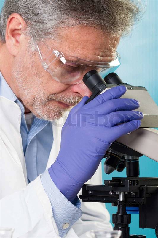 Focused senior life science professional routine screening the microscope slides in the cell laboratory. Lens focus on the researcher\'s face, stock photo