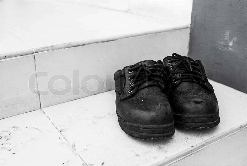 Pair of old dirty work boots in construction site, stock photo