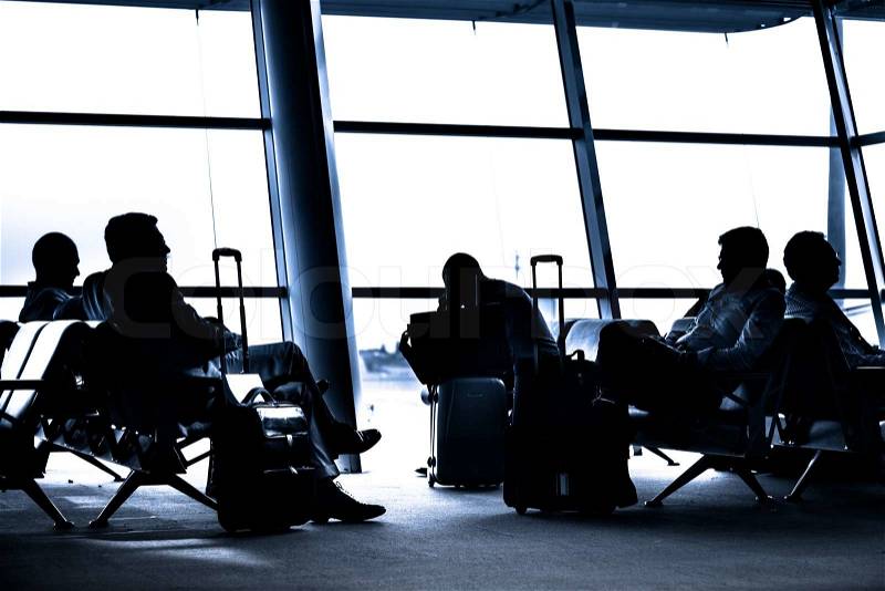 Silhouettes of business people traveling on airport; waiting at the plane boarding gates, stock photo