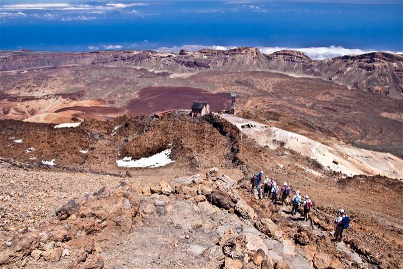 Group of senior hikers backpacking in the rough volcanic landscape on the volcano, Teide, highest peak of Spain, stock photo