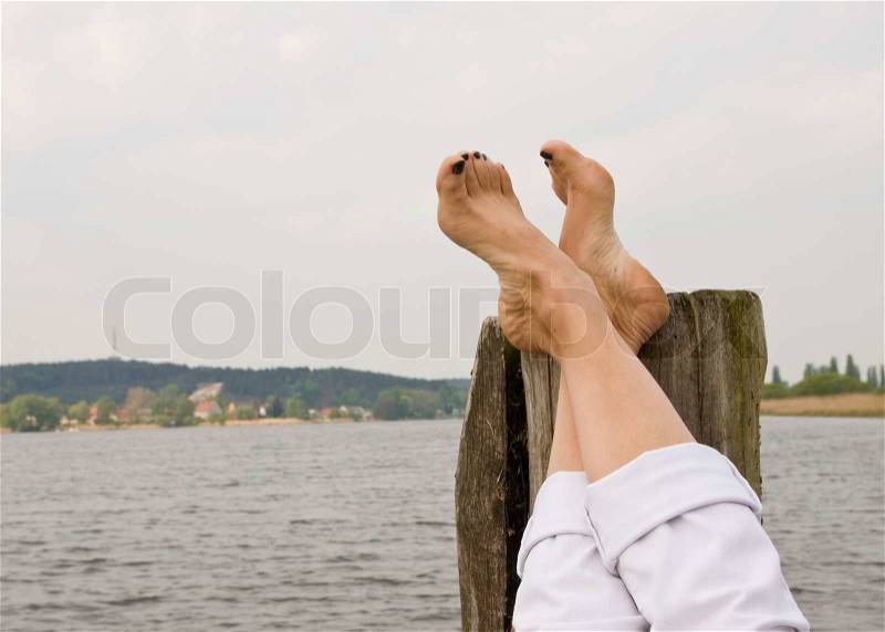 Cropped image of a woman\'s feet relaxing by a riverbank, stock photo