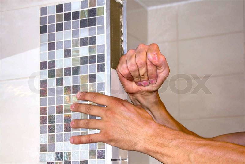 Worker puts tiles in the wall bathroom , stock photo
