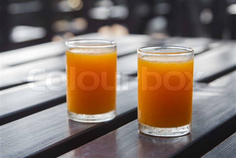 Glass of freshly orange juice on wooden table, stock photo