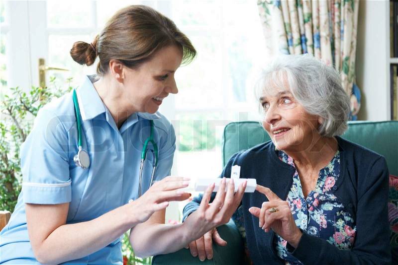 Nurse Advising Senior Woman On Medication At Home, stock photo