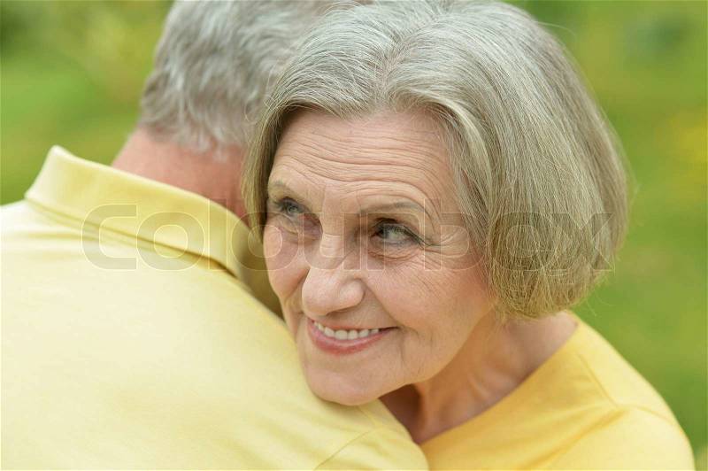 Happy elderly couple at nature on leaves background, stock photo