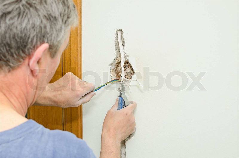 Certified electrician installing socket for light switch, stock photo