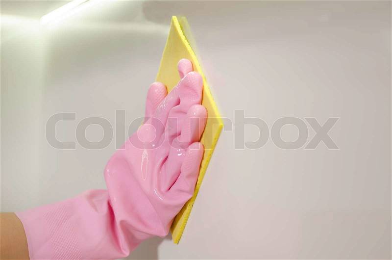 Gloved hand wiping a white surface with a cloth in a cleanliness, hygiene and household chores concept, stock photo