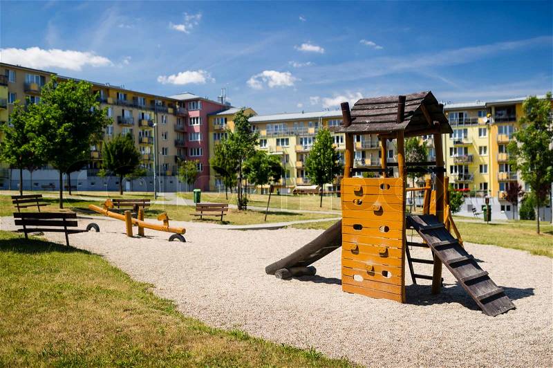Children playground in nature in front of row of newly built block of flats, stock photo