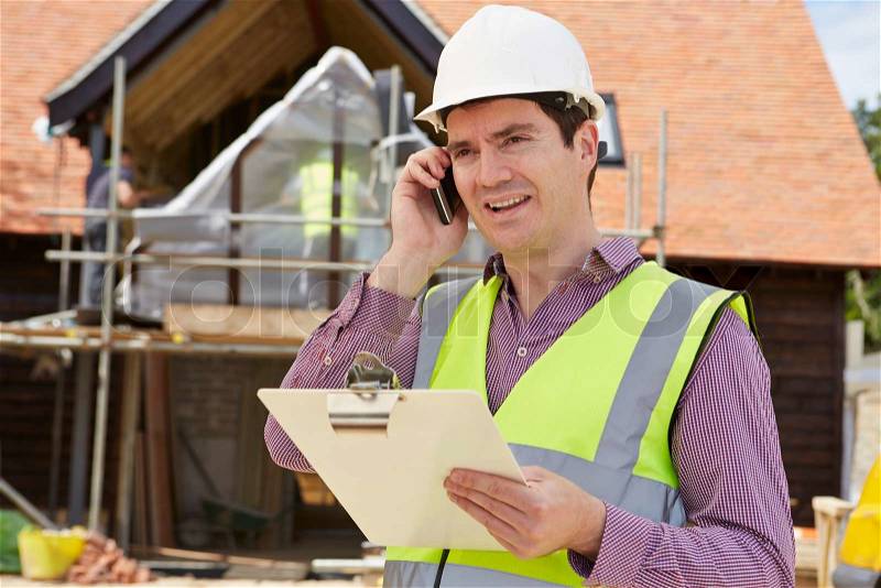 Architect On Building Site Using Mobile Phone, stock photo