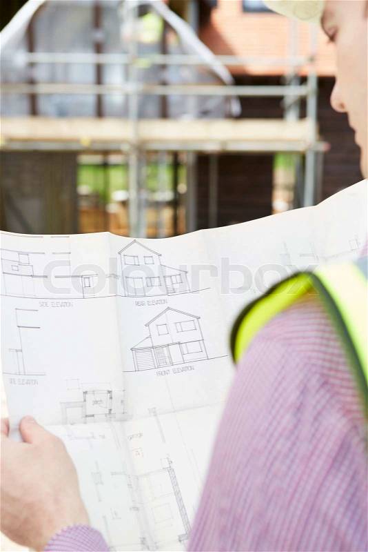 Architect On Building Site Looking At Plans For House, stock photo
