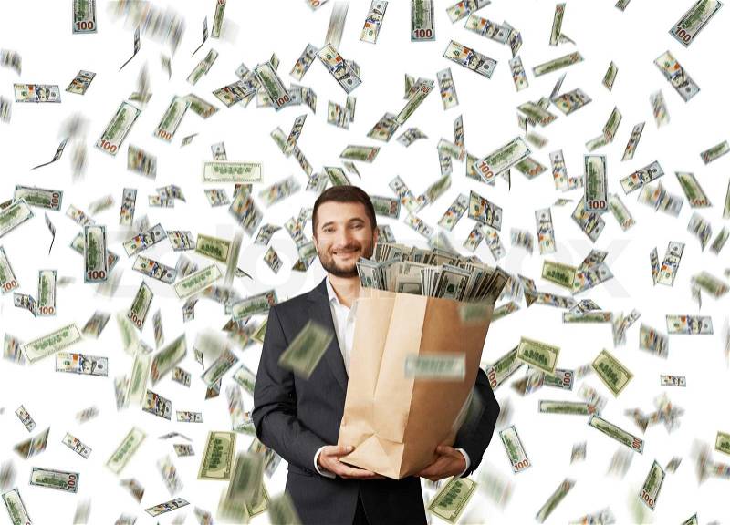 Happy and smiley businessman holding paper bag with money under dollar\'s rain, stock photo