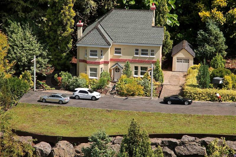Mini world, home with cars and a garage and real conifer in the sun, very creative, stock photo