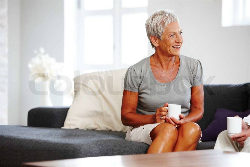 An elderly woman drinking coffee with her friend, stock photo