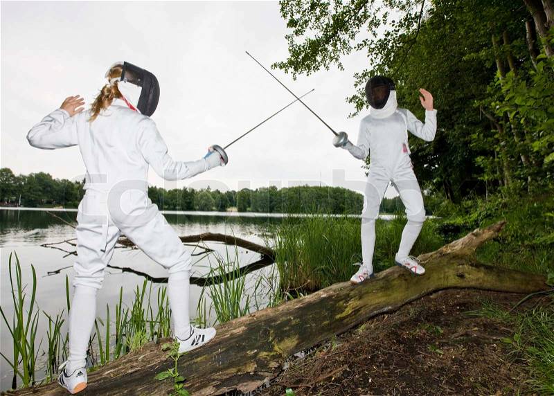 Two girls practice fencing in the woods, stock photo