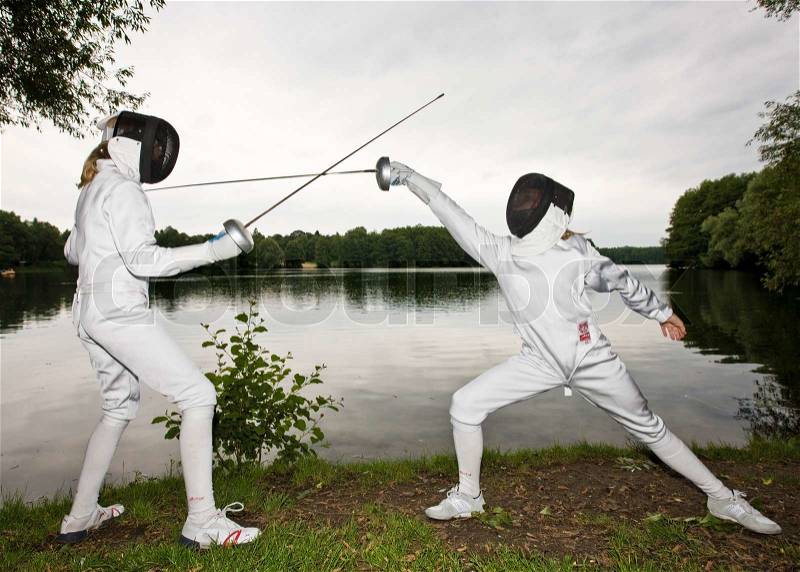 Two girls practice fencing in the woods, stock photo