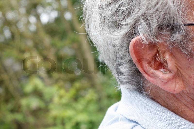 An elderly man with a hearing aid, stock photo