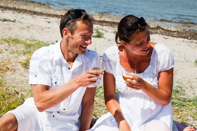 A caucasian couple holding a glass of white wine during a summer picnic, stock photo