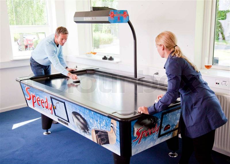 Business people having fun i the break/ recreation room. Colleagues playing air hockey in their recreation room/ break room, stock photo