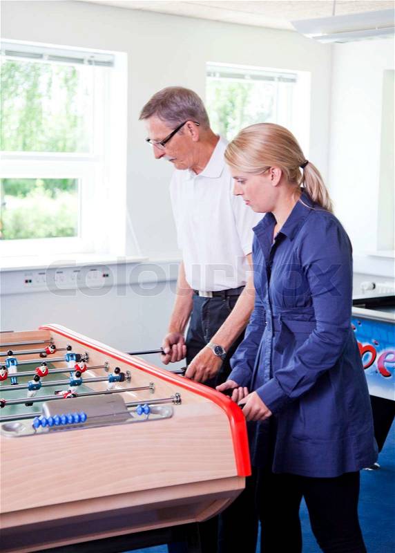 Business people having fun i the break/ recreation room. Colleagues playing tabletop football in the break room of their office. Business people havi, stock photo