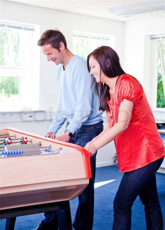 Business people having fun i the break/ recreation room. Colleagues playing tabletop football in the break room of their office. Business people havi, stock photo