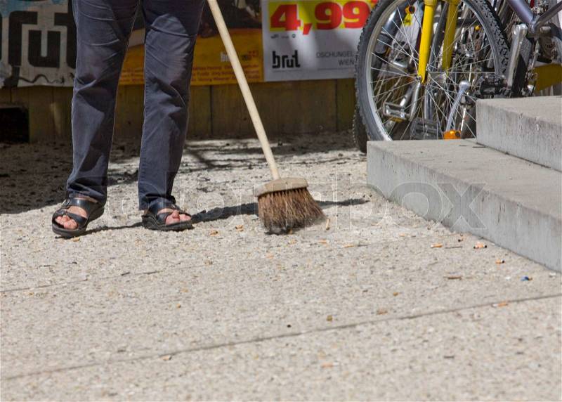 Cropped image of a woman sweeping the street, stock photo