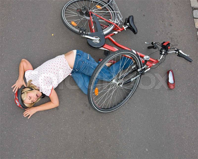 Top view of a female cyclist who falls from her bike during a road accident, stock photo
