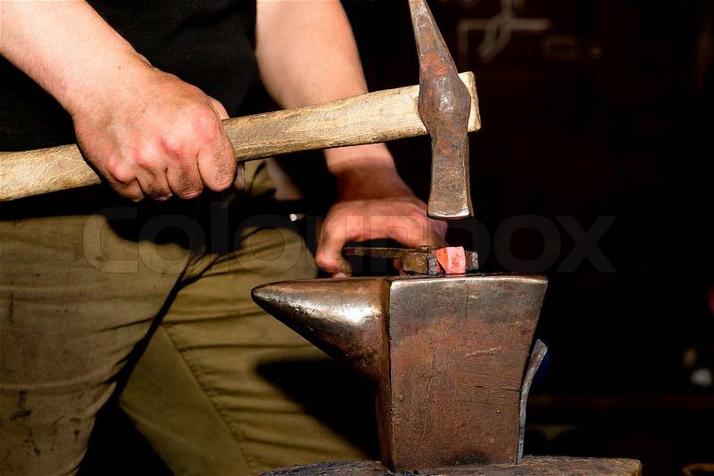 Forging process blacksmith hammering hot metal on an old antique anvil, stock photo
