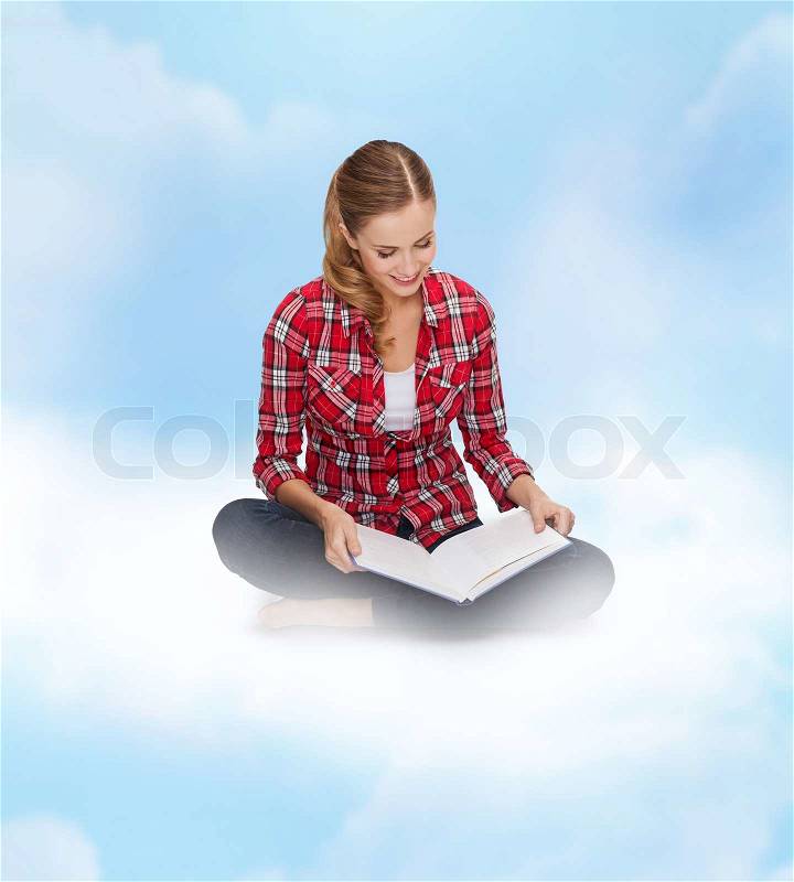 Education and leisure concept - smiling young woman sitting on floor with book, stock photo