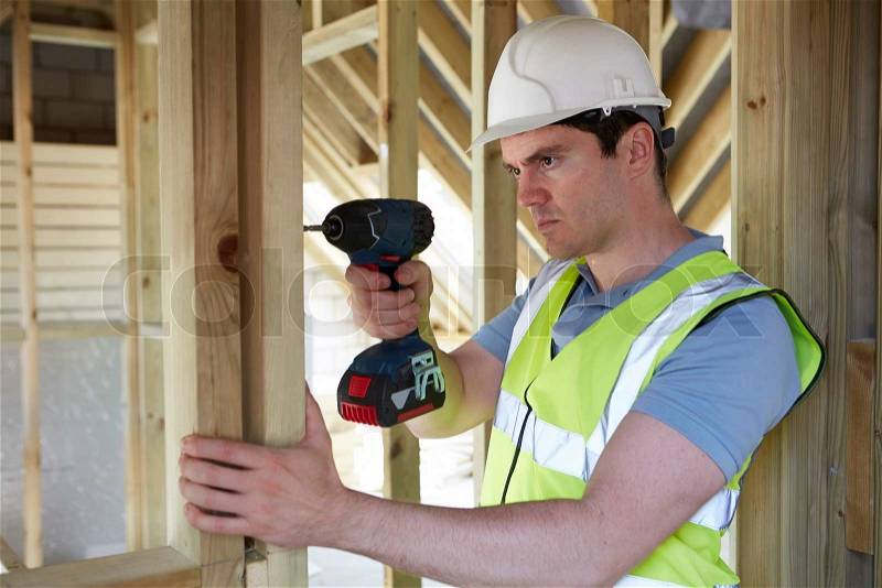 Construction Worker Using Cordless Drill On House Build, stock photo