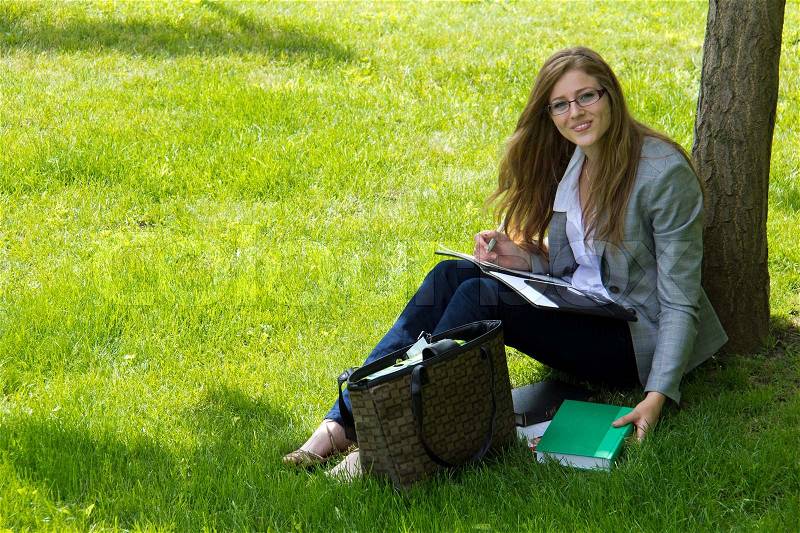 Female college student studies outside on campus, stock photo