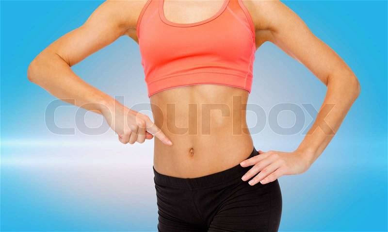 Fitness, exercise and diet concept - close up of woman pointing finger at her six pack, stock photo
