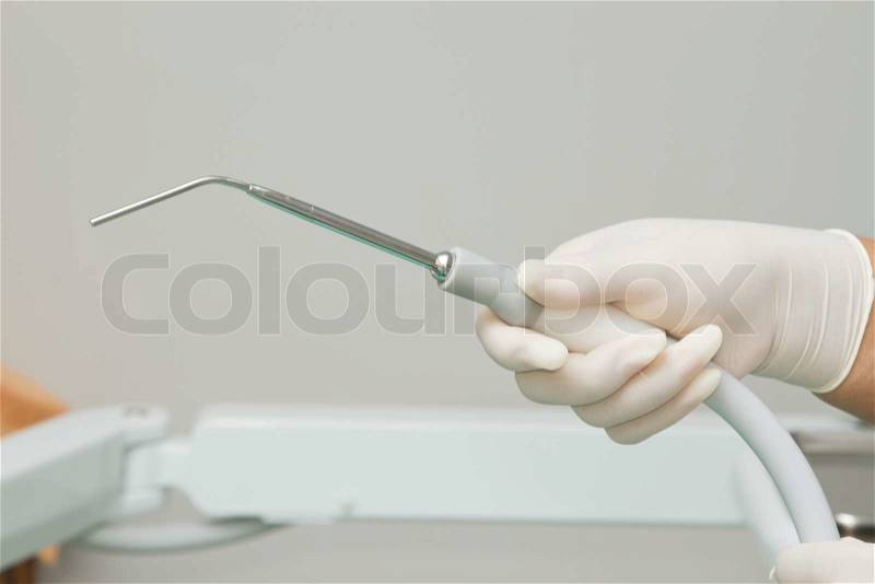 Dentist's hand holding dental tool in dental clinic, stock photo