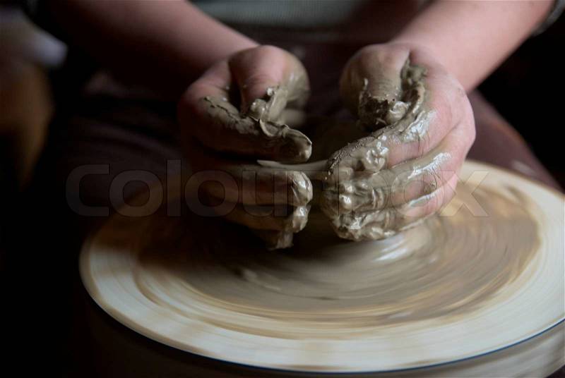 Female hands forming clay pot on the pottery wheel , stock photo