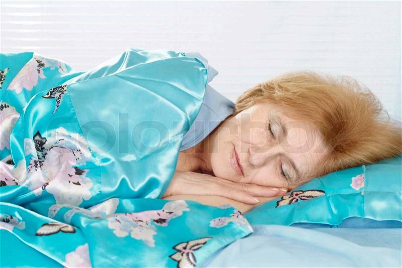 Beautiful older woman sleeping in bed at home, stock photo
