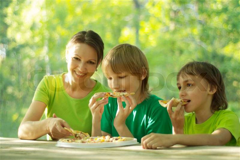 Happy cute family eat pizza together outdoors, stock photo