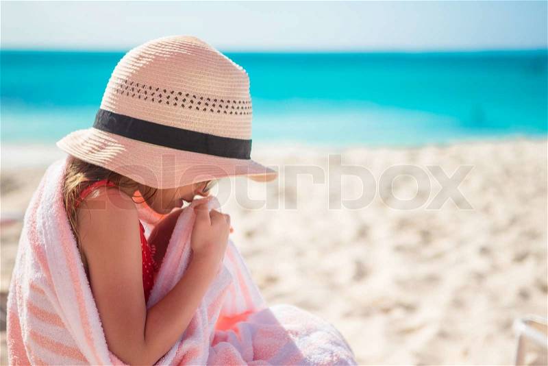 Little girl sitting on chair at beach during summer vacation, stock photo