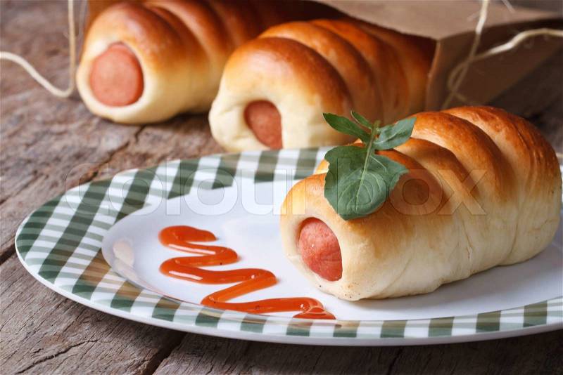 Roll with sausage on a plate with ketchup and arugula closeup horizontal , stock photo