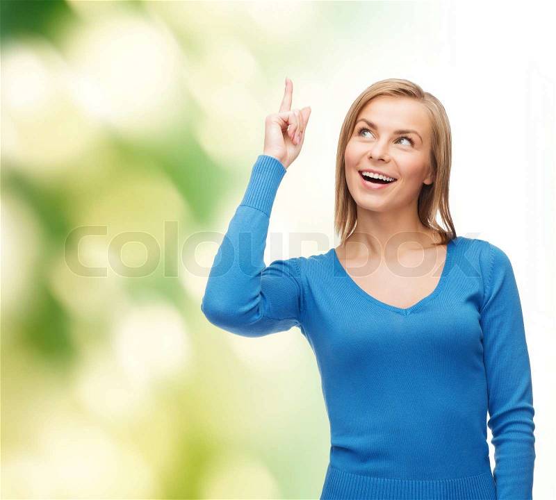 Advertisement concept - attractive young woman in casual clothes pointing her finger up, stock photo