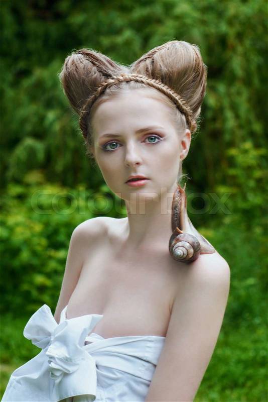Naked young woman with fashion hairstyle and big snail on her shoulder, stock photo