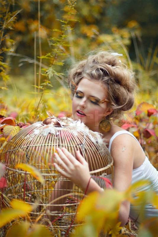 Beautiful fairy girl with golden cage in a forest, stock photo