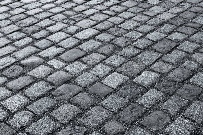 Old wet stone paved avenue street road, low angle after rain, stock photo