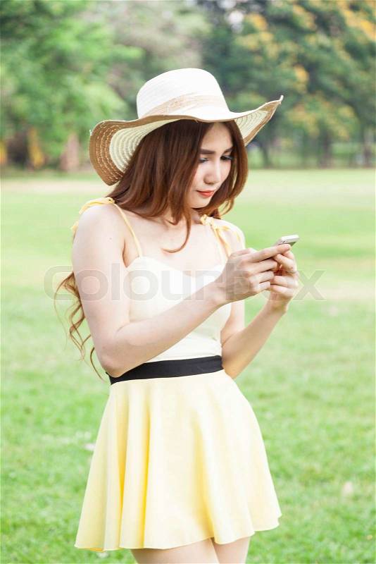 Woman play smart phones. Woman with hat standing in a park with a phone, stock photo